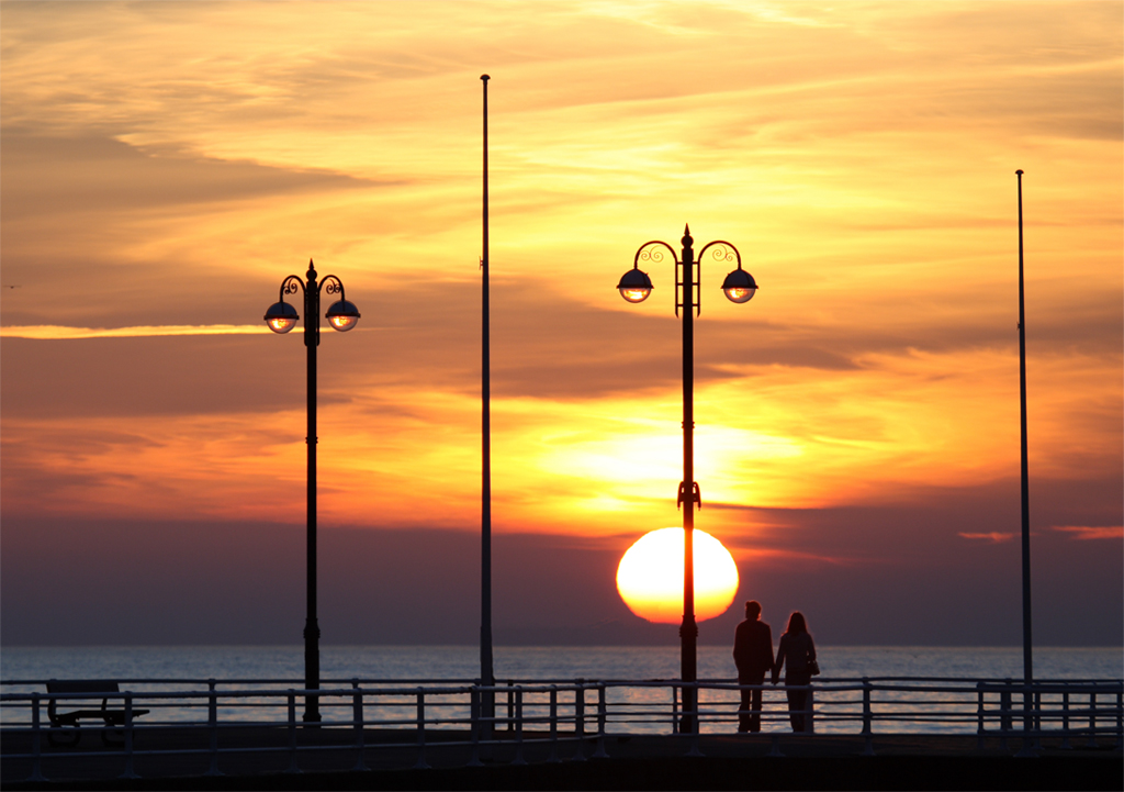 Couple holding hands, looking at the Sunset at Aberystwyth